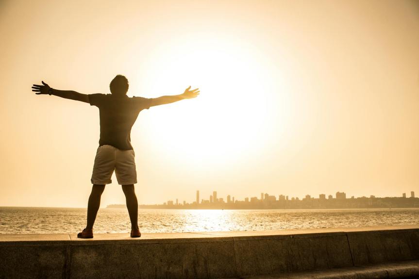 man standing on ledge while spreading arms